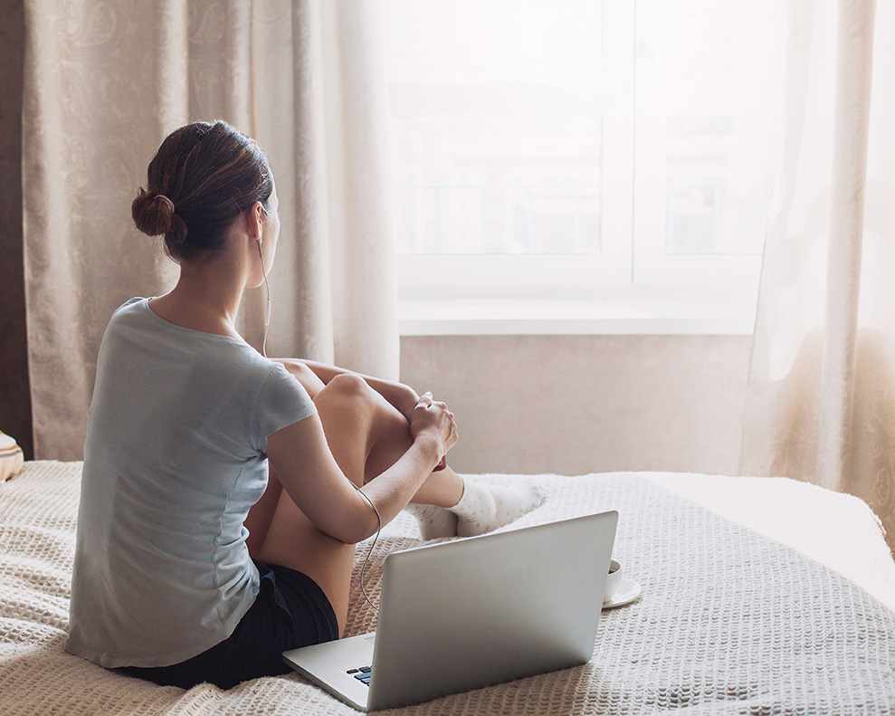 Young woman on the bed with a laptop preparing for infertility counseling in North Carolina