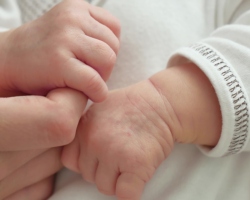 Mother holding newborn's hand. Perinatal Mental health therapist