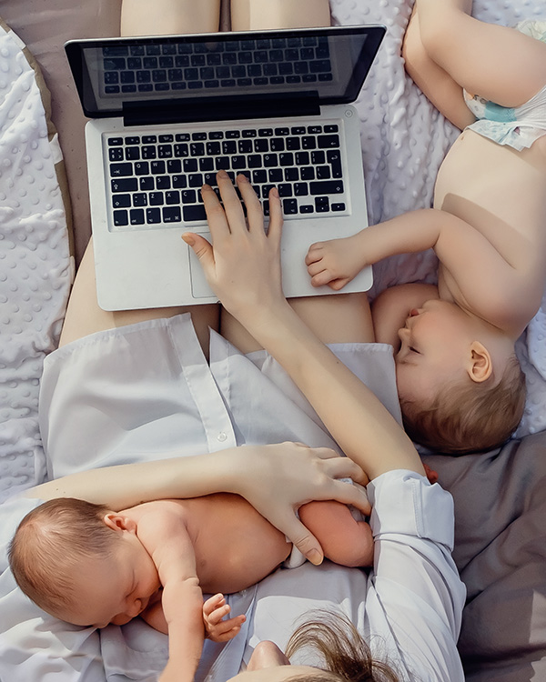 Twin babies with mom using a laptop for perinatal therapy with Christina Rush